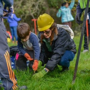 a woman and a child planting a sapling at a park